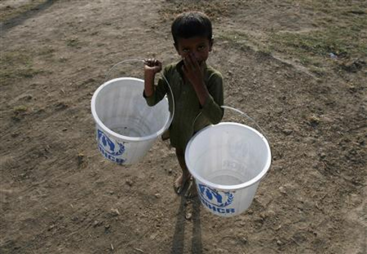 A flood victim carries buckets which he will fill up with water from a hand pump while taking refuge with his family in a relief camp in Sukkur