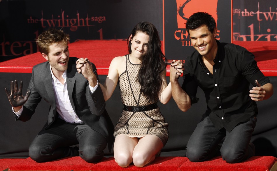 Actors Robert Pattinson left, Kristen Stewart and Taylor Lautner hold hands after putting their handprints in cement during a hand and footprint ceremony at the Grauman039s Chinese Theatre in Hollywood, California on November 3, 2011.