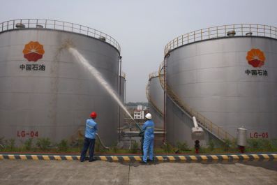 Employees spray water to cool down oil tanks at a PetroChina oil storage facility in Suijing, Sichuan Province, China