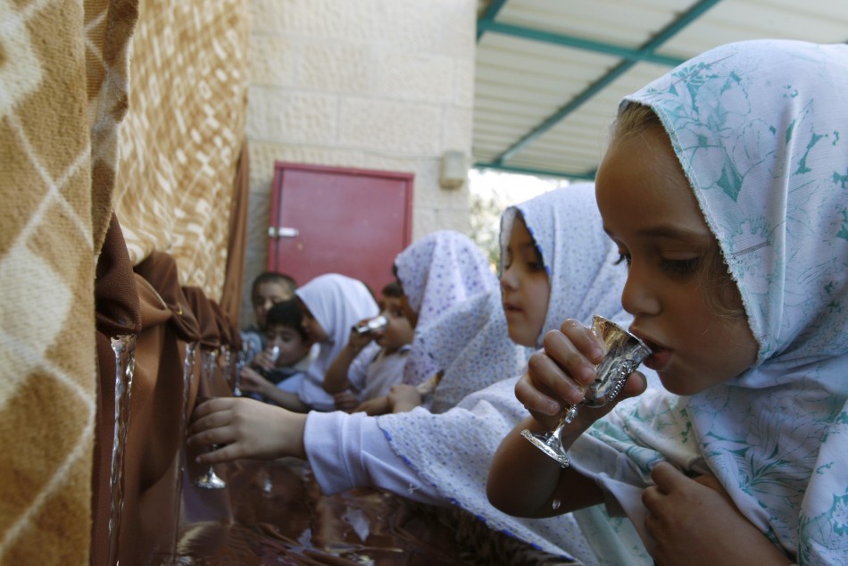 Palestinian schoolchildren drink water as they simulate the annual Muslim pilgrimage of Hajj in Nablus