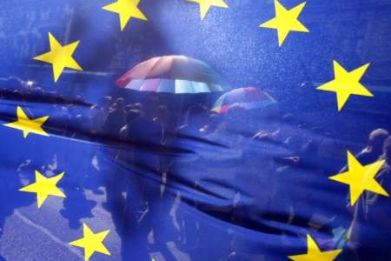 People walk behind the European Union's flag