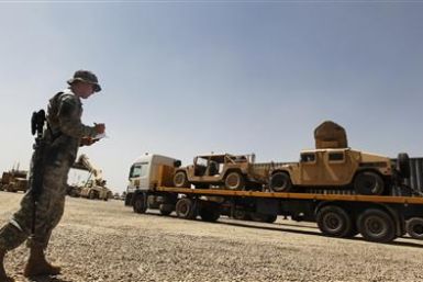 A U.S. Soldier takes down the vehicle numbers of humvees loaded up on a trailer as they prepare to leave Iraq at Balad Base