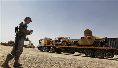A U.S. Soldier takes down the vehicle numbers of humvees loaded up on a trailer as they prepare to leave Iraq at Balad Base
