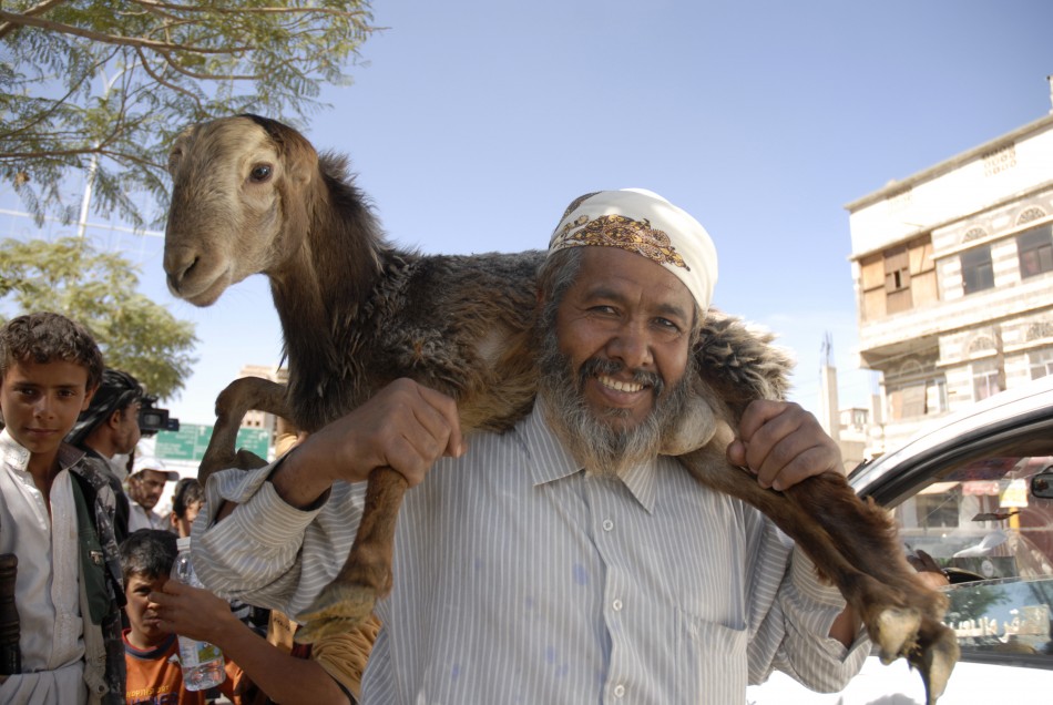 A man carries a sacrificial goat on sale at a market, ahead of the Eid al-Adha feast, in Sanaa, Yemen