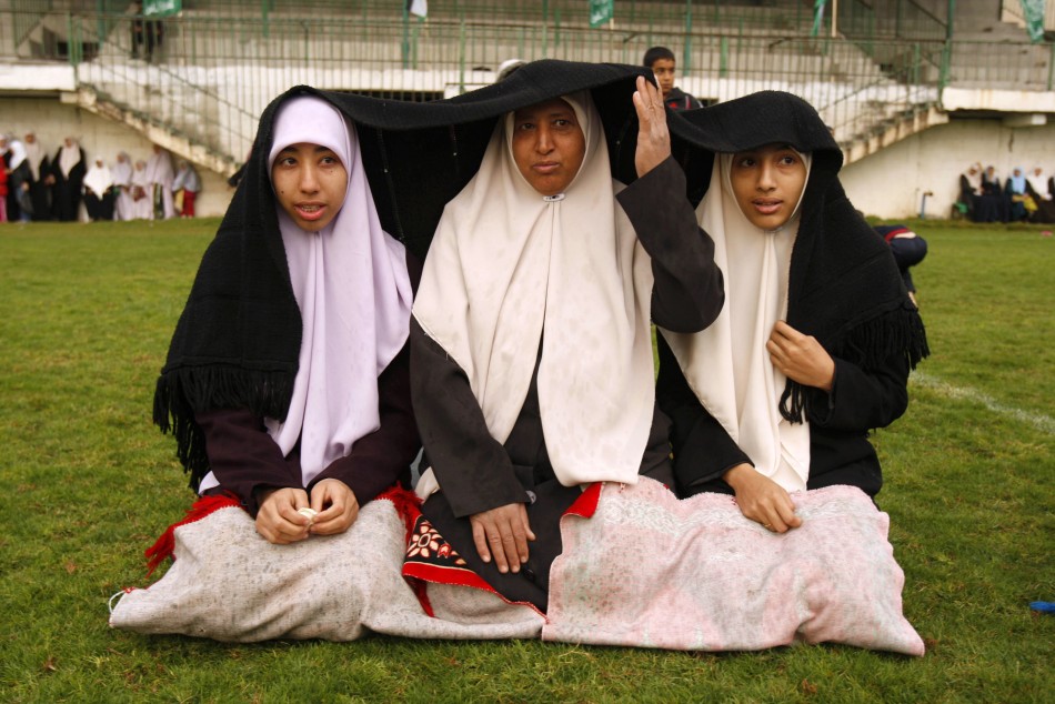 Palestinian women take cover from rain during Eid al-Adha prayers in Gaza City