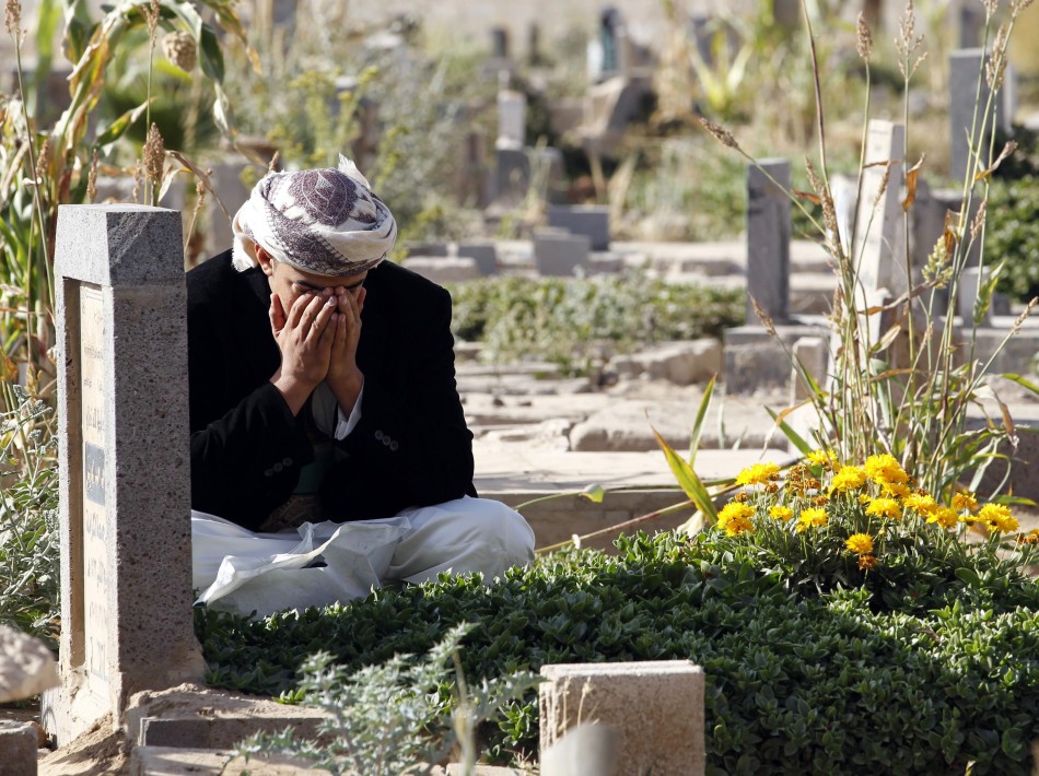 A man reacts next to his grave in a cemetery during the Muslim festival of Eid al al-Adha in Sanaa