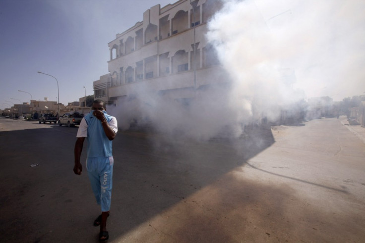 A man covers his face as he walks past a truck spraying smoke to mask the smell of corpses and to ward off insects attracted to the stench in the streets of Sirte City