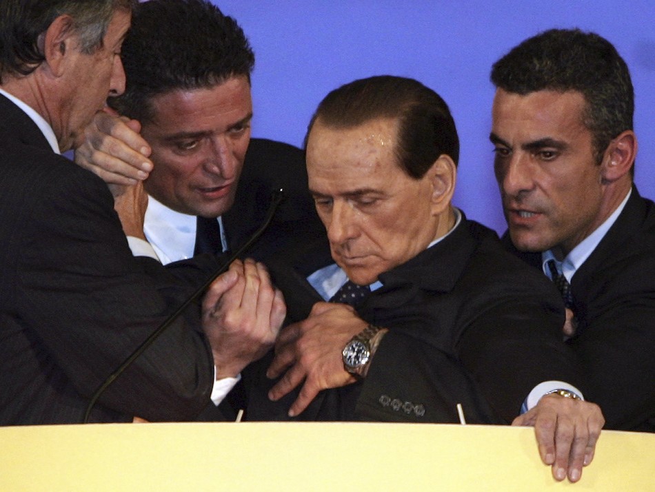 Silvio Berlusconi is assisted by aides after collapsing in Tuscany