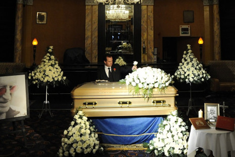 Funeral director Robert Morphet stands by the coffin of British entertainer Jimmy Saville, as it is displayed to the public at The Queens Hotel in Leeds