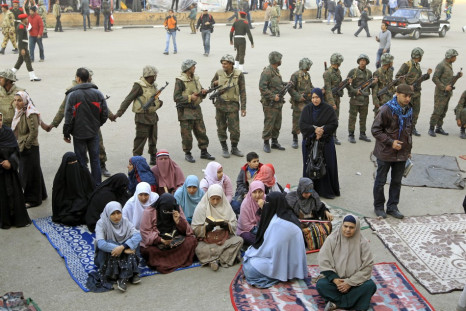 Women opposition supporters sit in front of Egyptian soldiers at Tahrir Square in Cairo