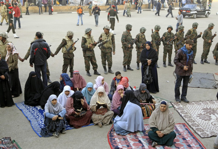 Women opposition supporters sit in front of Egyptian soldiers at Tahrir Square in Cairo