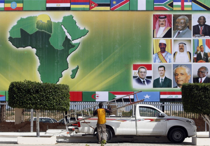 An organizer carries a ladder under a banner showing the African continent in Sirte