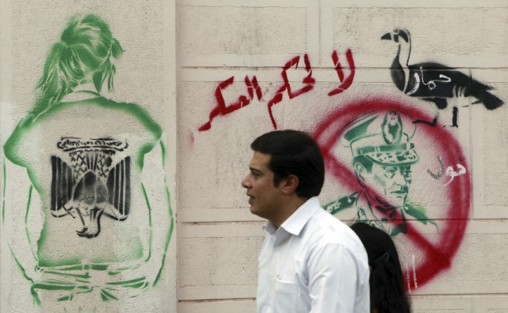 An Egyptian man walks past a graffiti of past a graffiti of former Egyptian President Hosni Mubarak and writing "Who is Protecting the Tyrant" at downtown in Cairo