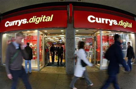 Pedestrians walk past a Currys.digital store in central London