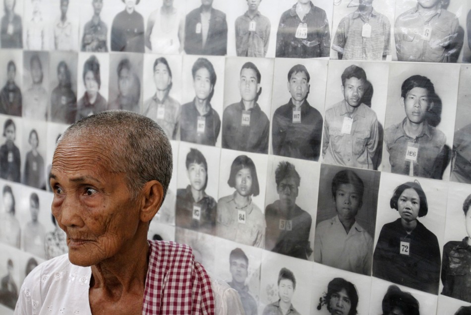 A survivor of the Khmer Rouge regime Hem Sakou stands in front of portraits of victims at the Tuol Sleng S-21 genocide museum in Phnom Penh