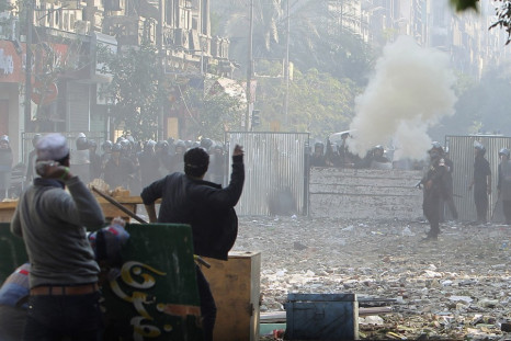 Protesters throw stones at police who are firing tear gas, during clashes near Tahrir Square in Cairo