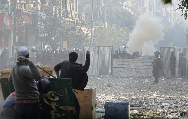 Protesters throw stones at police who are firing tear gas, during clashes near Tahrir Square in Cairo