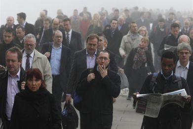 Commuters make their way in the fog across London Bridge towards the financial district of London