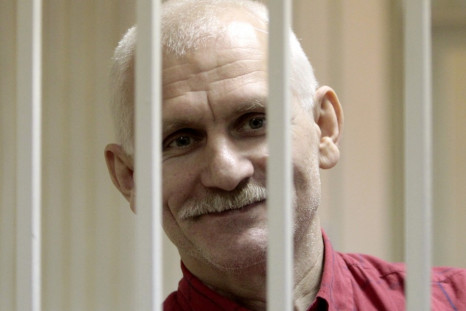 Human rights activist Bialiatski smiles inside a guarded cage in a courtroom in Minsk