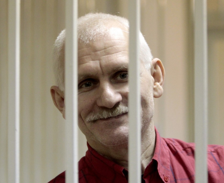 Human rights activist Bialiatski smiles inside a guarded cage in a courtroom in Minsk