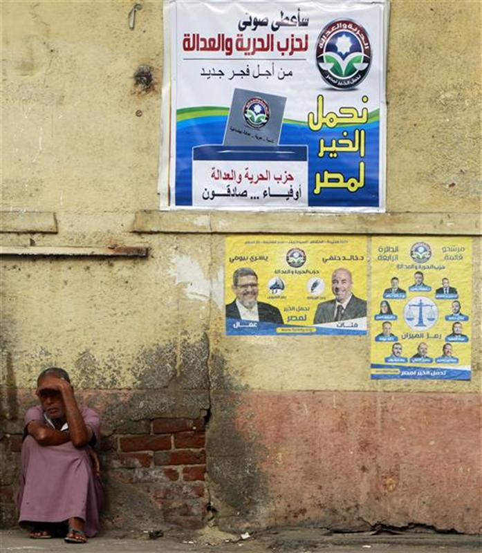 A beggar sits beside posters for parliamentary elections by Egypt's Muslim Brotherhood "The Freedom and Justice Party'" in Cairo A beggar sits beside posters for parliamentary elections by Egypt's Muslim Brotherhood "The Freedom and Justice Party'" in Cairo