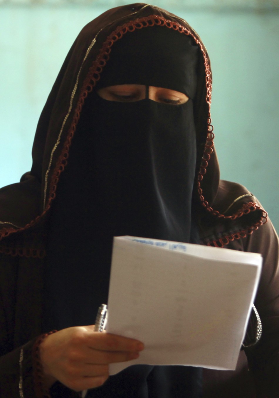 A woman reads her ballot paper before casting her vote at a polling station during the parliamentary election in Cairo