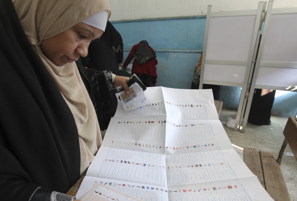 A woman reads her ballot paper before casting her vote at a polling station during the parliamentary election in Cairo