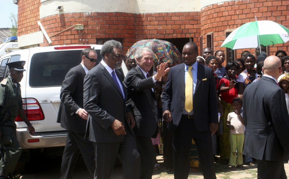 Former US President George Bush c flanked by co-director of cervical cancer prevention program Dr Groesbeck Parham l and Zambias Minister for Lusaka Province Miles Sampa r waves to mothers at George Clinic where he launched the Red Ribbon Pink Ribb