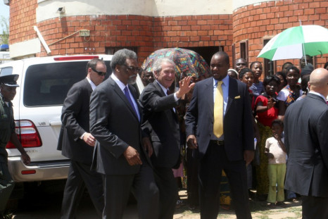 Former US President George Bush (c) flanked by co-director of cervical cancer prevention program Dr Groesbeck Parham (l) and Zambia's Minister for Lusaka Province Miles Sampa (r) waves to mothers at George Clinic where he launched the Red Ribbon Pink Ribb