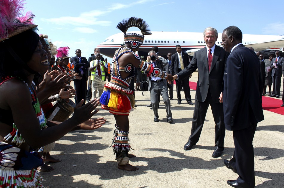 Former U.S. President Bush greets a traditional dancer on arrival at the Kenneth Kaunda International Airport in the capital Lusaka