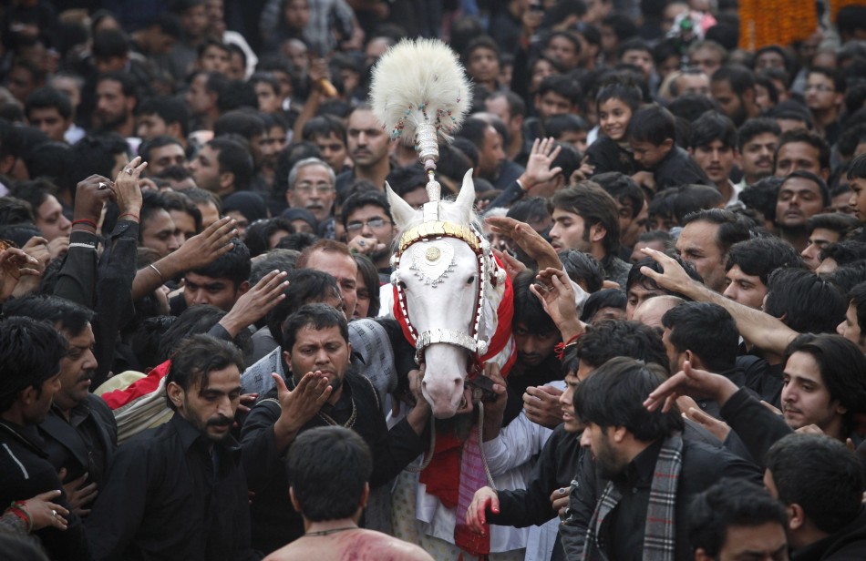Shiite Muslim men touch a symbolic sacred horse for good luck as they take part in a religious procession ahead of the Ashura festival in Lahore