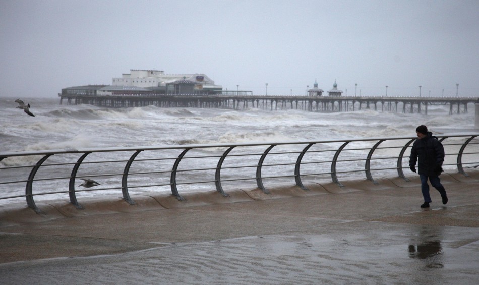 A man braves the wind and rain to walk her dog along the sea front near Blackpool