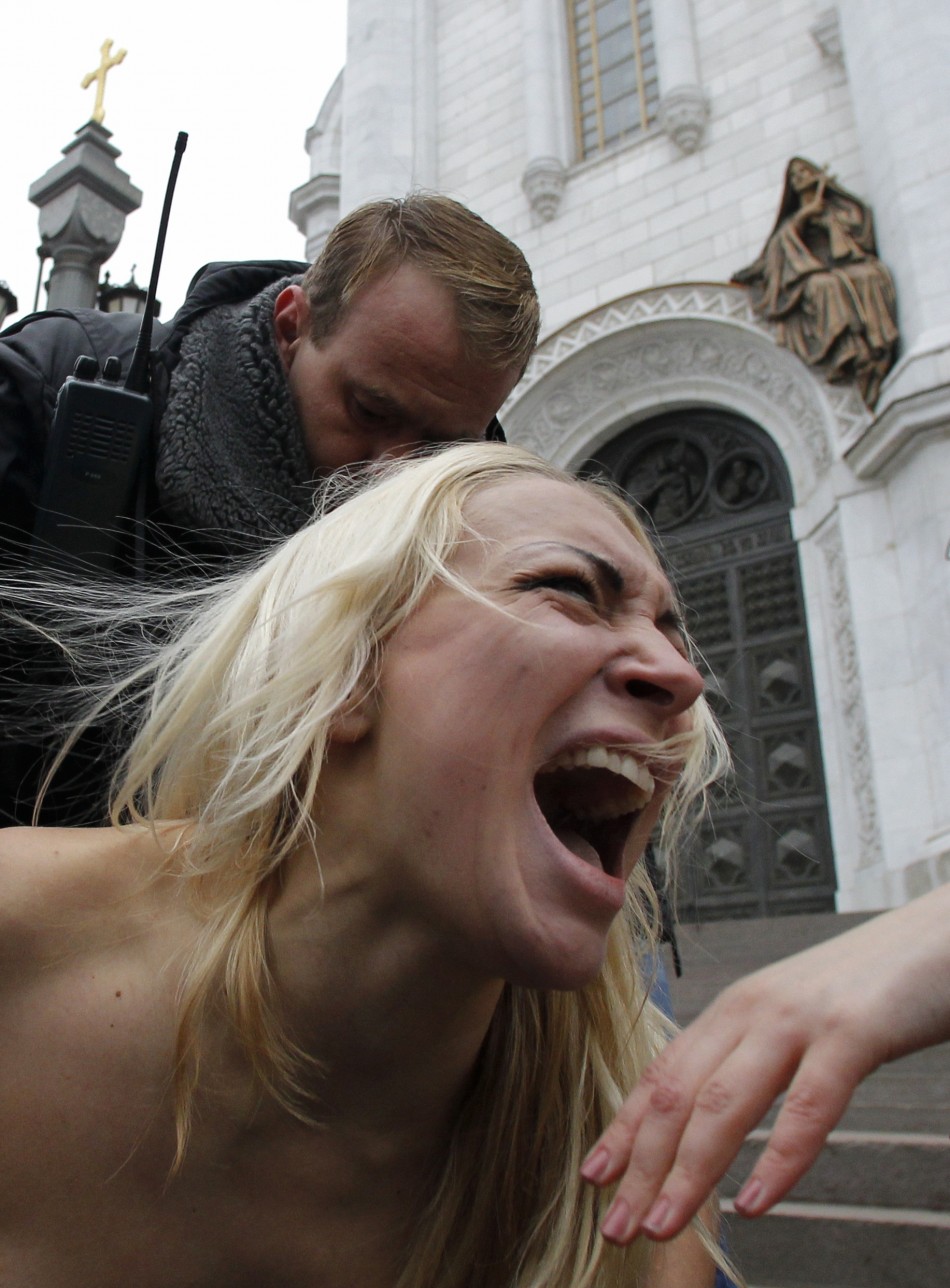 Security guards detain activists from Femen in front of the Cathedral of Christ the Saviour in Moscow Denis