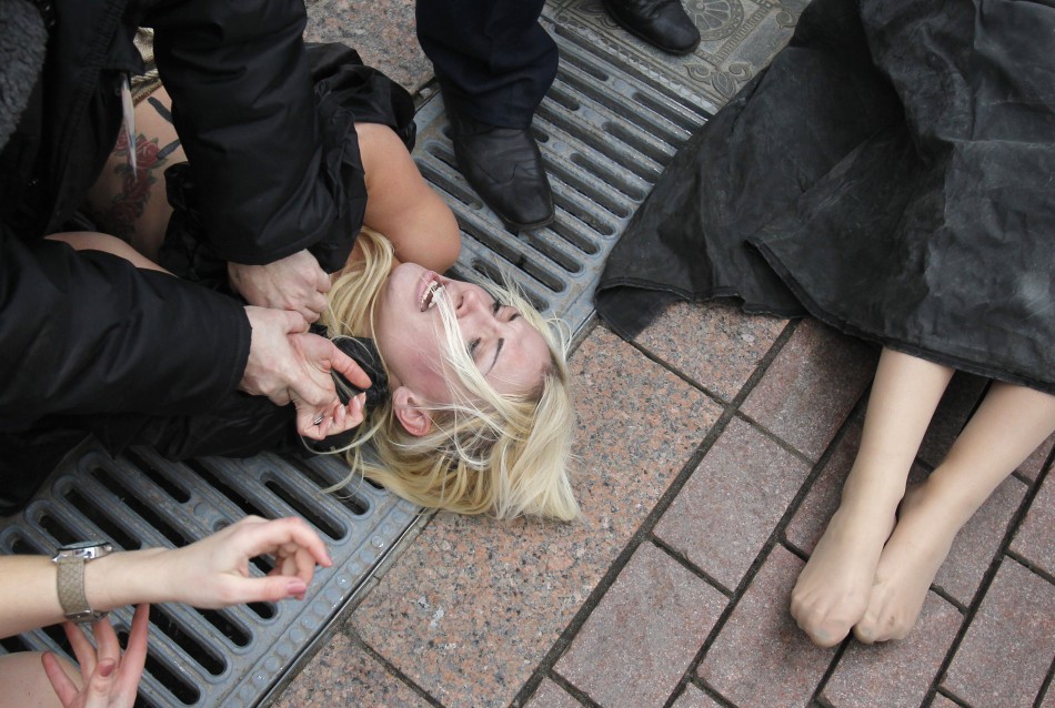 Security guards detain activists from Femen in front of the Cathedral of Christ the Saviour in Moscow