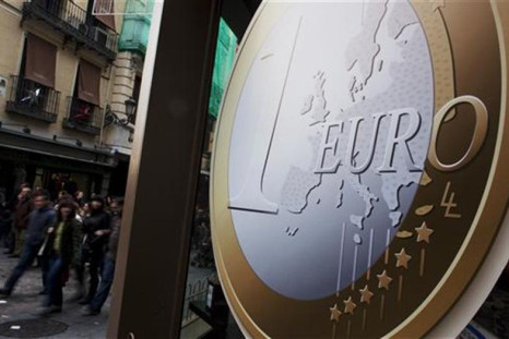 People walk past a pizza shop with a sign of a euro coin used to advertise its prices in central Madrid
