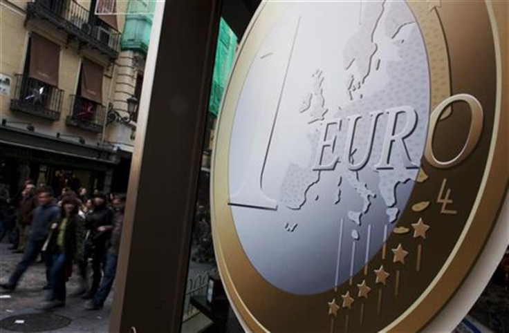 People walk past a pizza shop with a sign of a euro coin used to advertise its prices in central Madrid