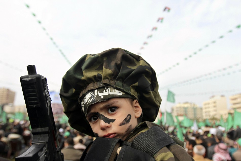 A boy wearing an Al-Qassam Brigades headband is carried by his father during a Hamas rally in Gaza City