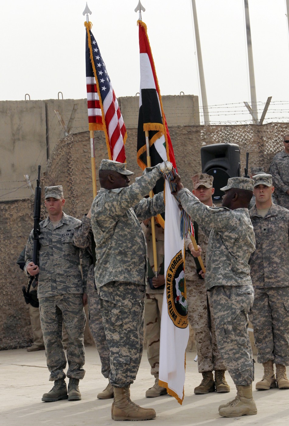 Members of the U.S. military retire its ceremonial flags signifying the end of their presence in Iraq at the Baghdad Diplomatic Support Center