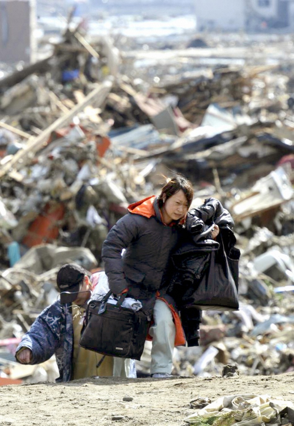 A woman carries her belongings away from her tsunami-stricken home