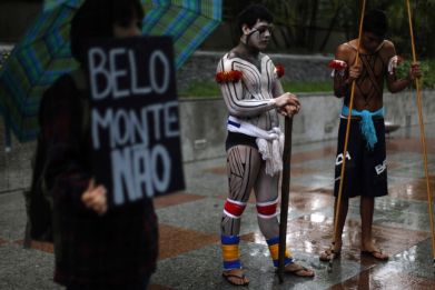 Brazilian indigenous men stand next to an environmental activist as he holds a banner that reads &quot; Belo Monte, No&quot; during a protest in Sao Paulo