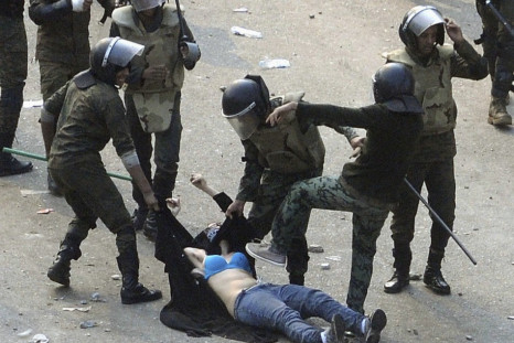 Egyptian army soldiers arrest a female protester during clashes at Tahrir Square in Cairo