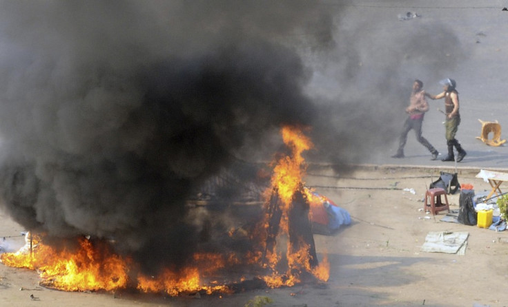 An Egyptian army soldier (R) arrests a protester near a burning tent during clashes at Tahrir Square in Cairo