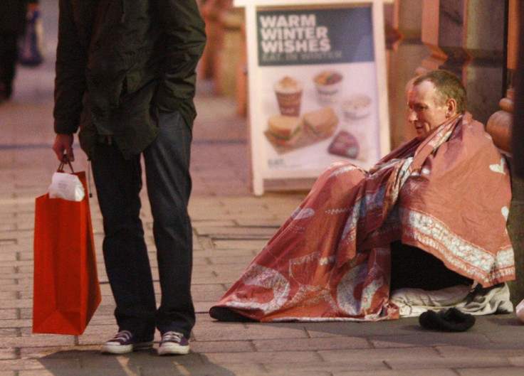 A homeless man sits outside the entrance to Green Park Tube Station on Christmas Eve in central London