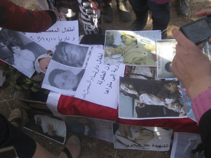 People take pictures of posters during a protest against Syria's President Assad in Daria near Damascus