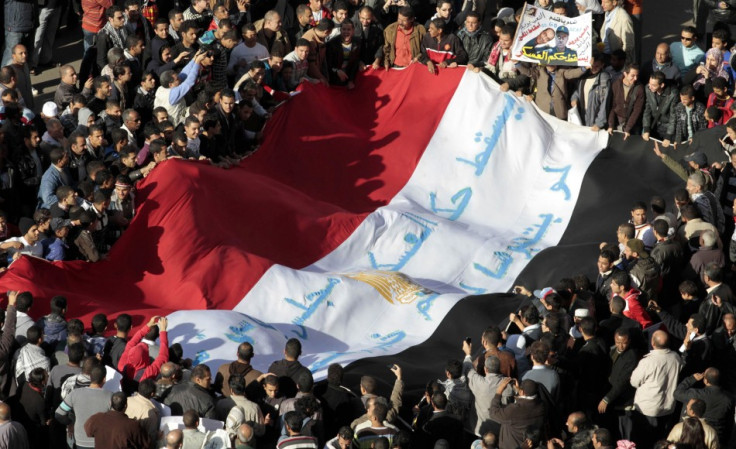 Egyptian protesters shout anti-military council slogans as they hold a national flag in Cairo