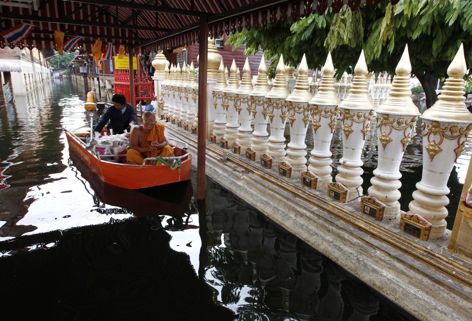 A Buddhist monk takes a boat around a flooded temple in Bangkok