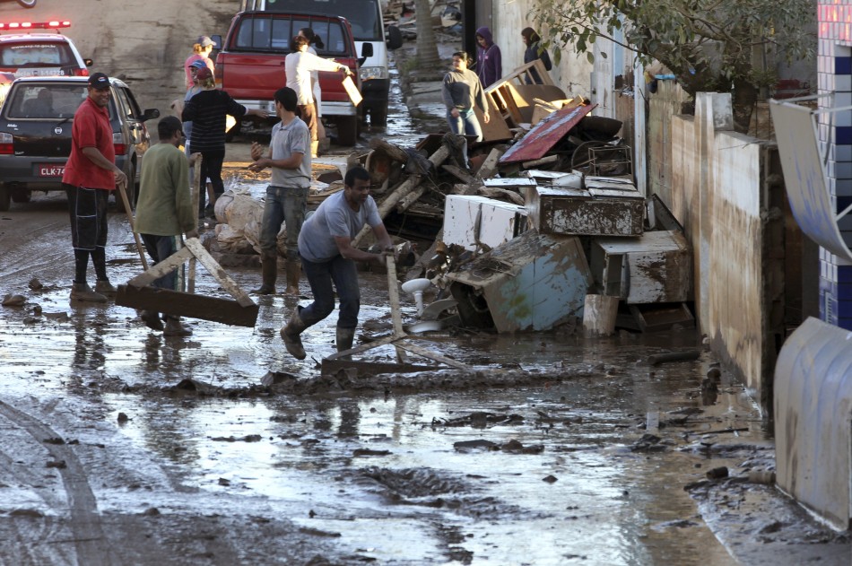 Residents clear a mud-covered street after floodwaters recede in the Ribeira do Iguape riverside suburb of Eldorado
