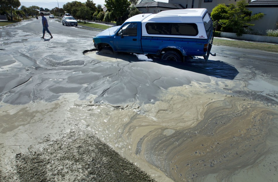 Sewage sweeps past a car trapped in a sink hole after earthquakes in Christchurch