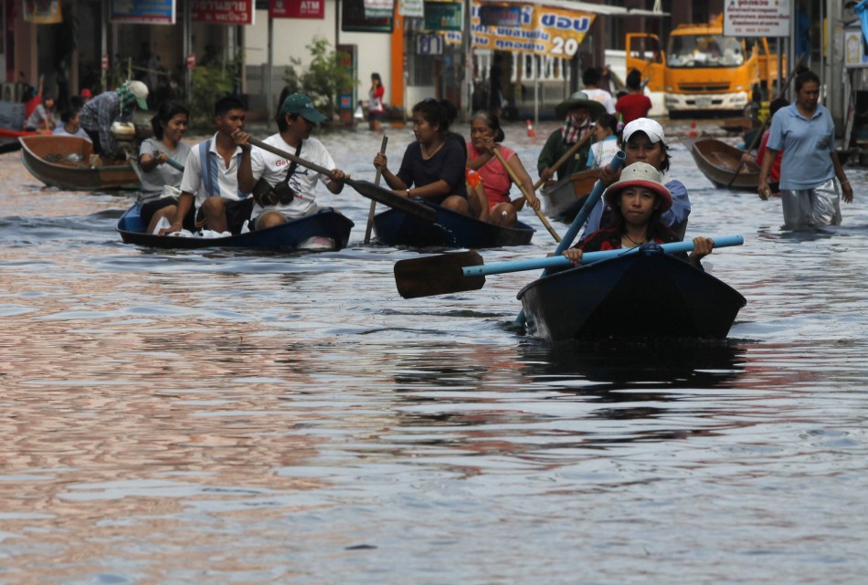 Flood-hit residents paddle through a flooded street in Nonthaburi province