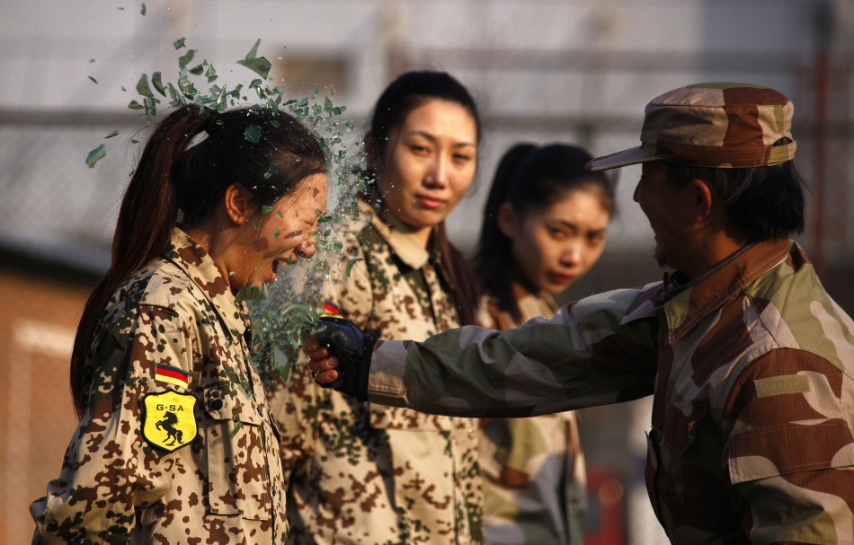An instructor from Tianjiao Special Guard Consultant Ltd smashes a bottle over a female recruits head during a training session